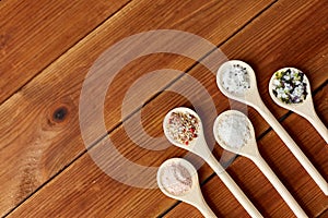 Spoons with salt and spices on wooden table