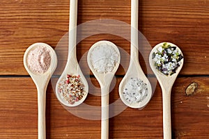 Spoons with salt and spices on wooden table