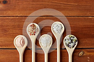 Spoons with salt and spices on wooden table