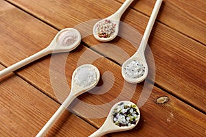 Spoons with salt and spices on wooden table