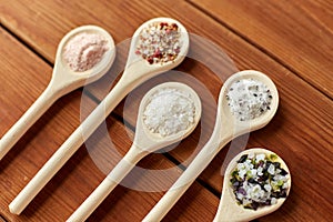 Spoons with salt and spices on wooden table