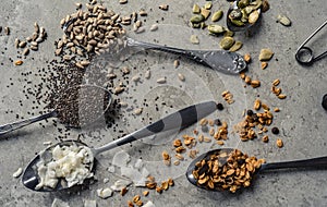 Spoons with sunflower seeds, chia pepitas granola and coconut flakes on table photo