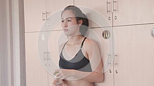 Sport Asian woman opening private locker in locker room and putting drinking pure water bottle after relax breaking from workout