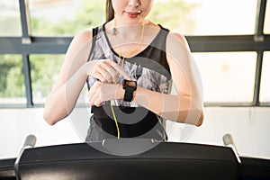 Sport asian woman running treadmill. smartwatch to listening mus