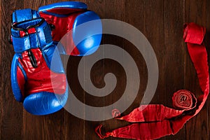 Sport background with blue and red gloves and red bandage on wooden background.