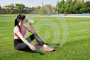 Sport background with copy space . woman athlete takes a break, she drinking water, out on a run on a hot day . concept of healthy