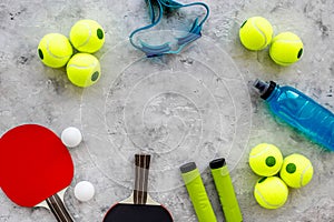 Sport background. Sport gear. Table tennis racket, tennis balls, hand expander on grey background top view copyspace