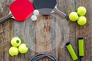 Sport background. Sport gear. Table tennis racket, tennis balls, hand expander on wooden background top view copyspace