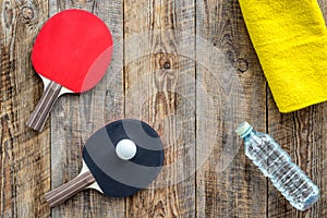 Sport background. Traning cocept. Ping pong racket, towel and water on wooden background top view copyspace