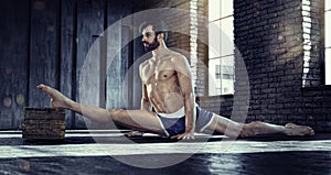 Sport backgrounds. Young athletic man doing split.