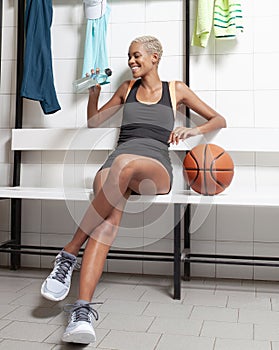 Sport basketball player in the locker room, a African American female athlete drinking water, before or after the game,