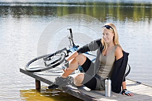 Sport biking young woman sitting by lake