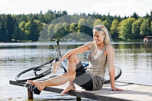 Sport biking young woman sitting by lake