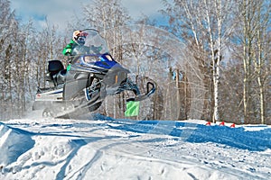 Sport blue snowmobile jump. Sunny winter day with blue sky. Concept quick movement. photo