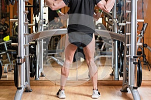 Sport, bodybuilding, lifestyle and people concept - young man with barbell doing squats in gym.