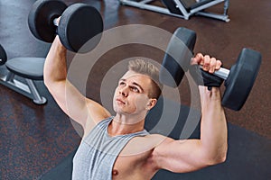 Sport, bodybuilding, training and people concept - young man with dumbbell flexing muscles. men working with dumbbells his body at