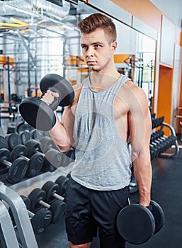 Sport, bodybuilding, training and people concept - young man with dumbbell flexing muscles. men working with dumbbells his body at