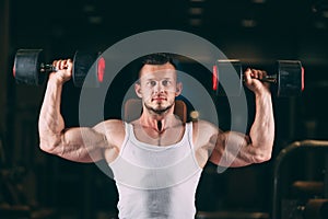 Sport, bodybuilding, weightlifting, lifestyle and people concept - young man with dumbbells flexing muscles in gym