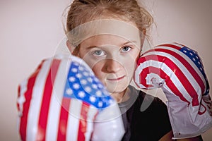 Sport and boxing training concept. Portrait of young cute child girl fighter with boxing gloves in flag of USA