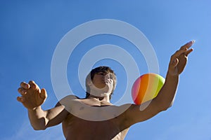 Sport build teenager with ball and blue sky