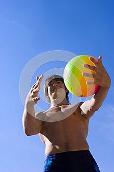 Sport build teenager with variegated ball and sky