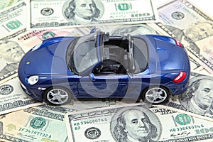 Sport car model on pile of US dollar banknotes