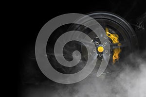 Sport car wheel with with yellow breaks and lot of smoke tire