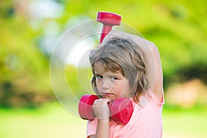 Sport child boy with strong biceps muscles. Kids exercising fitness dumbbells. Strong little boy exercising with