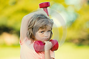 Sport child boy with strong biceps muscles. Kids exercising fitness dumbbells. Strong little boy exercising with