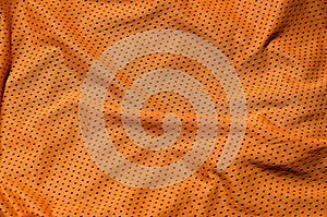 Sport clothing fabric texture background. Top view of orange polyester nylon cloth textile surface. Colored basketball shirt with