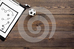 Sport coach concept. Pad with tactic plan of the match near whistle and football ball on wooden background top view copy