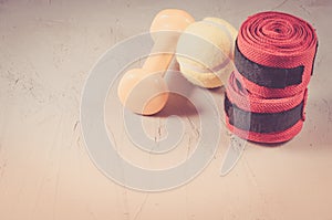 sport concept with dumbbell, yellow ball and bandage/sport concept with dumbbell, yellow ball and bandage on a stone background.