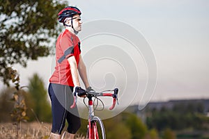 Sport Concepts. Male Cyclist Resting Outdoors on His Bike on Nature Background With Professional Outfit