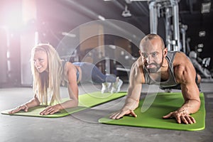 Sport couple doing plank exercise workout in fitness centrum. Man and woman practicing plank in the gym