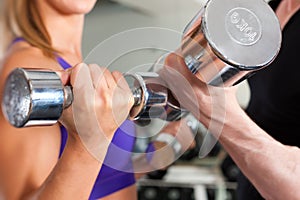 Sport - couple is exercising with barbell in gym