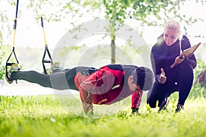 Sport couple outdoors with sling trainer