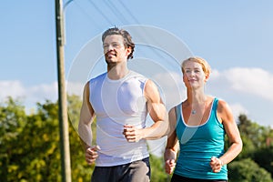 Sport couple running and jogging on rural street