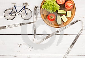 Sport and diet concept - bicycle model, fresh vegetables and ce