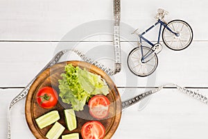 Sport and diet concept - bicycle model, fresh vegetables and ce