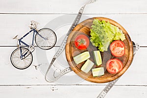 Sport and diet concept - bicycle model, fresh vegetables and ce