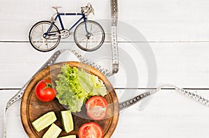 Sport and diet concept - bicycle model, fresh vegetables and ce