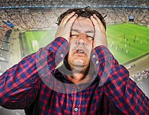 Sport emotion conceptual portrait of nervous and dejected soccer supporter man and football pitch background gesturing desperate