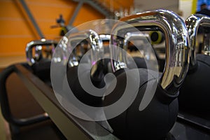 Sport equipment in gym. Small stylish weight black kettlebell stand row on horizontal rack