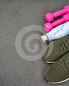 Sport equipment. Sport shoes, pink dumbbells on black background