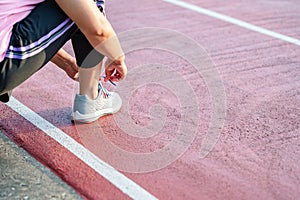 sport, exercise concept. runner woman wearing sports shoes for running, jogging on running track in stadium morning. people