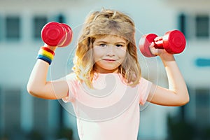 Sport exercise for kids. Sporty children, healthy Lifestyle. Child boy lifting dumbbells outside. Funny excited child