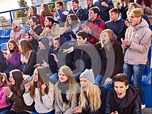 Sport fans clapping and singing on tribunes.