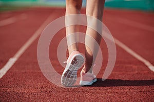Sport. Female legs in pink sneakers on running track stadium. Close-up on sports shoes of a running woman. Concept run
