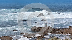 Sport fisherman on the shore of a sea with a fishing rod next to rocks