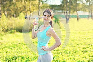 Sport and fitness concept - beautiful smiling woman drinking water from bottle